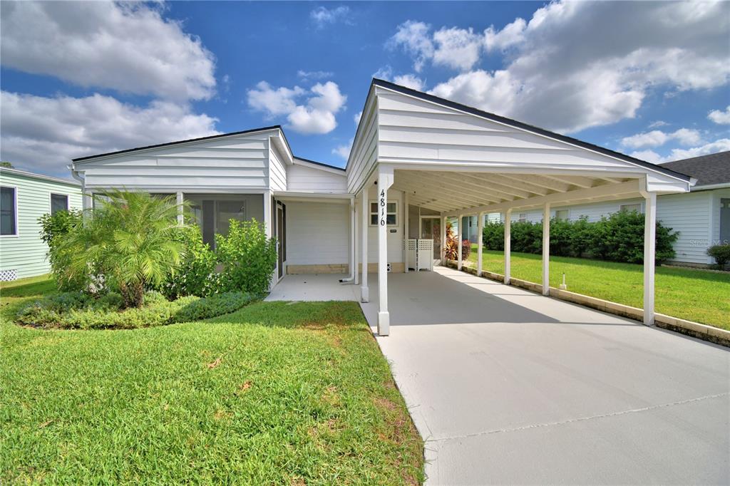 A white single-story house features a large attached carport and a front screened porch — 4816 GOLDENVIEW LANE, LAKELAND, FL