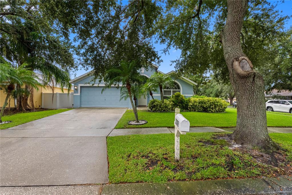 A light blue single-story house with a two-car garage and a large front yard — 3306 PIN OAK LANE, TAMPA, FL