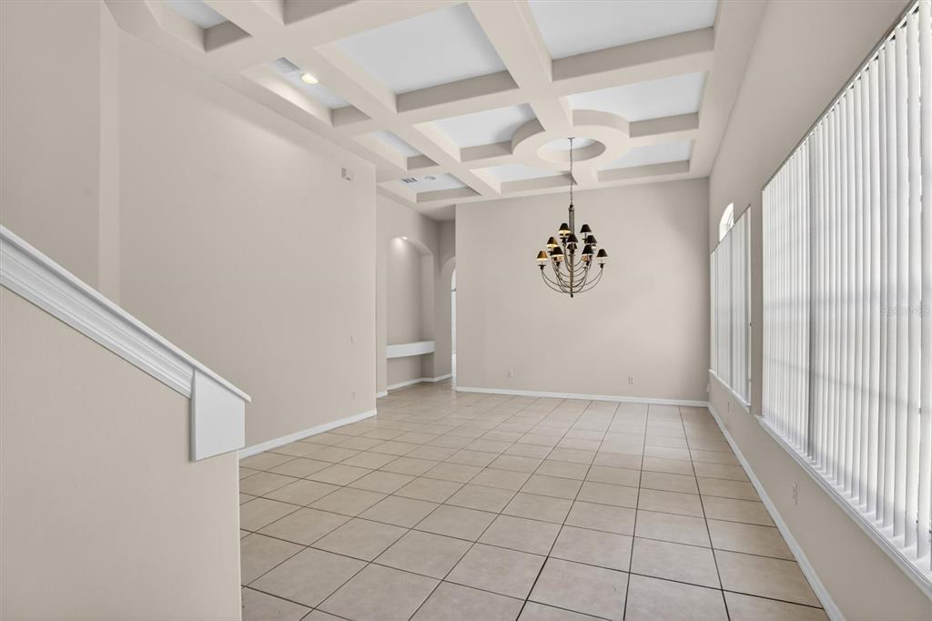 A dining room with a coffered ceiling, tile flooring, and a hanging chandelier — 8506 SAINT MARINO BOULEVARD, ORLANDO, FL