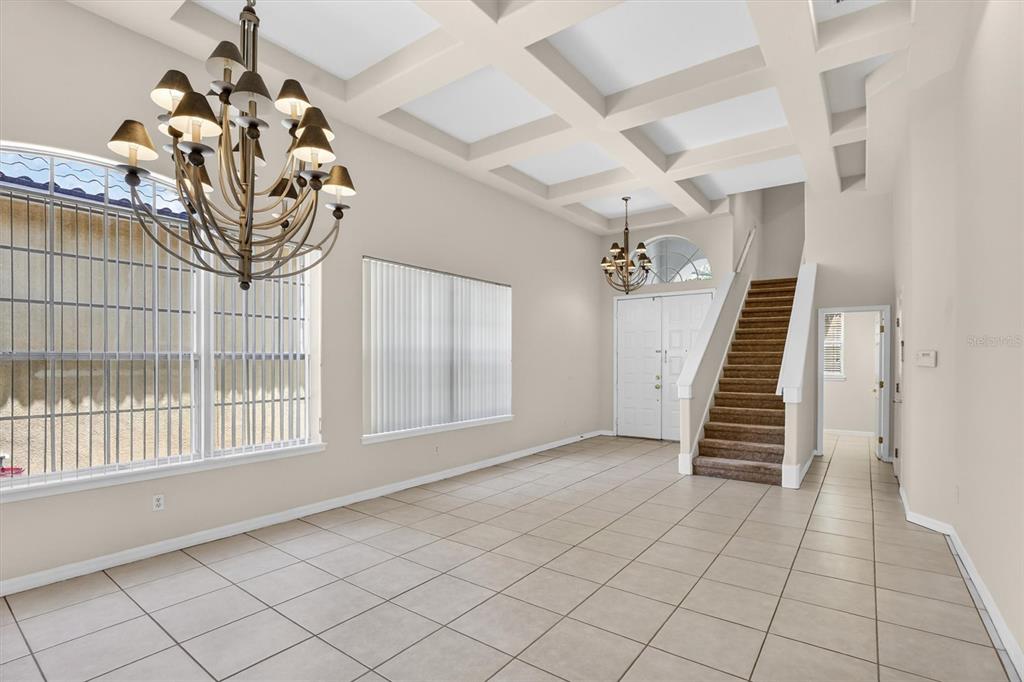 An entryway features a coffered ceiling, tile flooring, a staircase, and two chandeliers — 8506 SAINT MARINO BOULEVARD, ORLANDO, FL