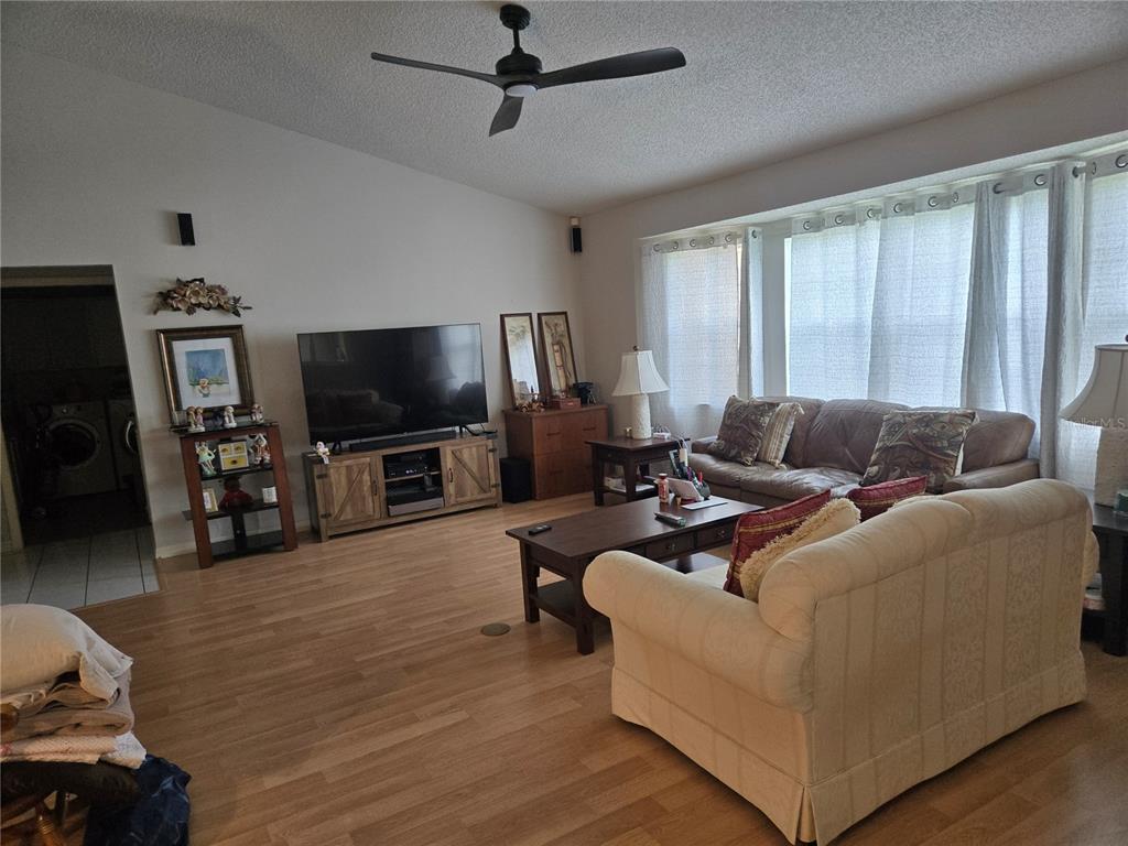 A living room features light wood flooring, a vaulted ceiling, and two sofas — 5506 PRINCE CHARLES LANE, LEESBURG, FL