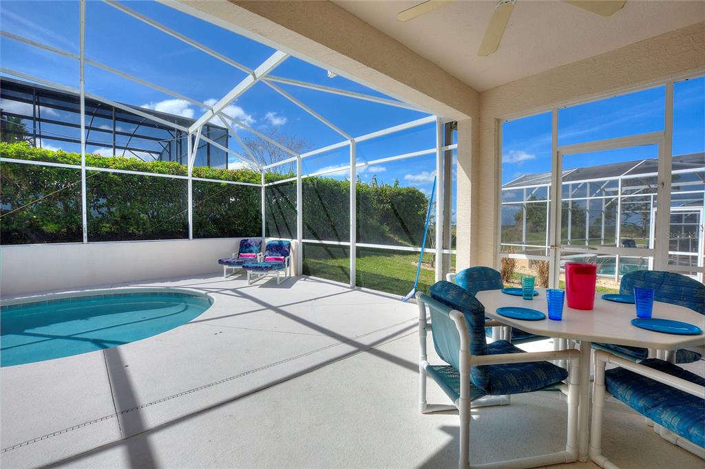 A screened-in patio features a small swimming pool, outdoor dining furniture, and a ceiling fan — 556 BONVILLE DRIVE, DAVENPORT, FL