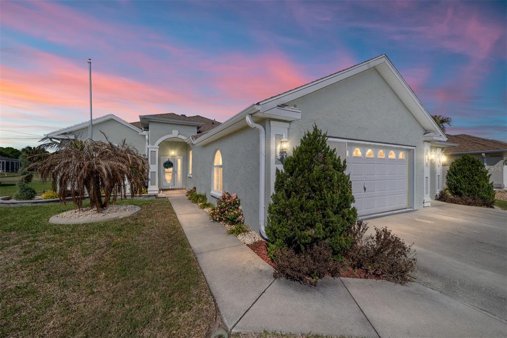 A single-story house with a light-colored stucco exterior, a two-car garage, and a concrete walkway — 5751 NW 25TH LOOP, OCALA, FL