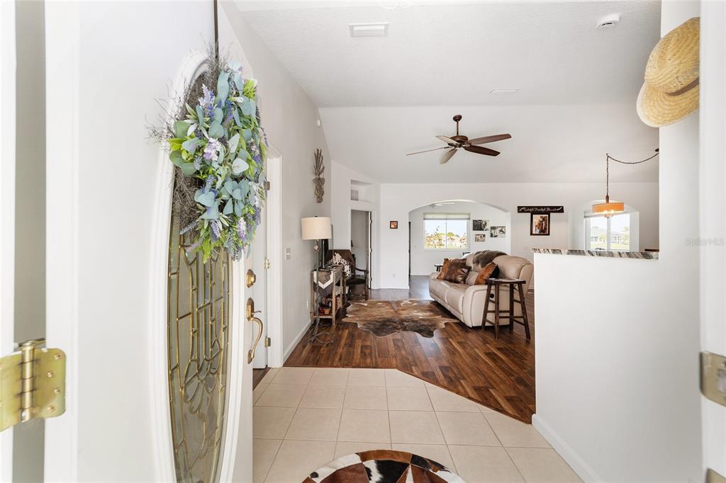 An entryway with tile flooring leads into a living room featuring wood floors and vaulted ceilings — 5751 NW 25TH LOOP, OCALA, FL