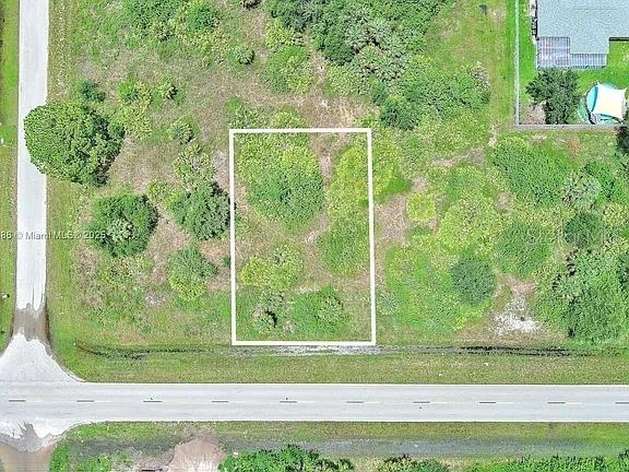 An aerial view shows a rectangular vacant lot outlined in white next to a road — 841 MILWAUKEE BOULEVARD, LEHIGH ACRES, FL