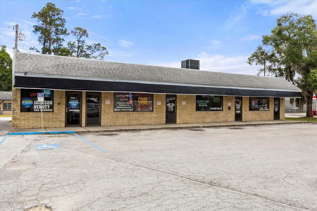 A single-story brick commercial building with multiple storefronts and a large paved parking lot — 5053 SE ABSHIER BLVD BOULEVARD, BELLEVIEW, FL