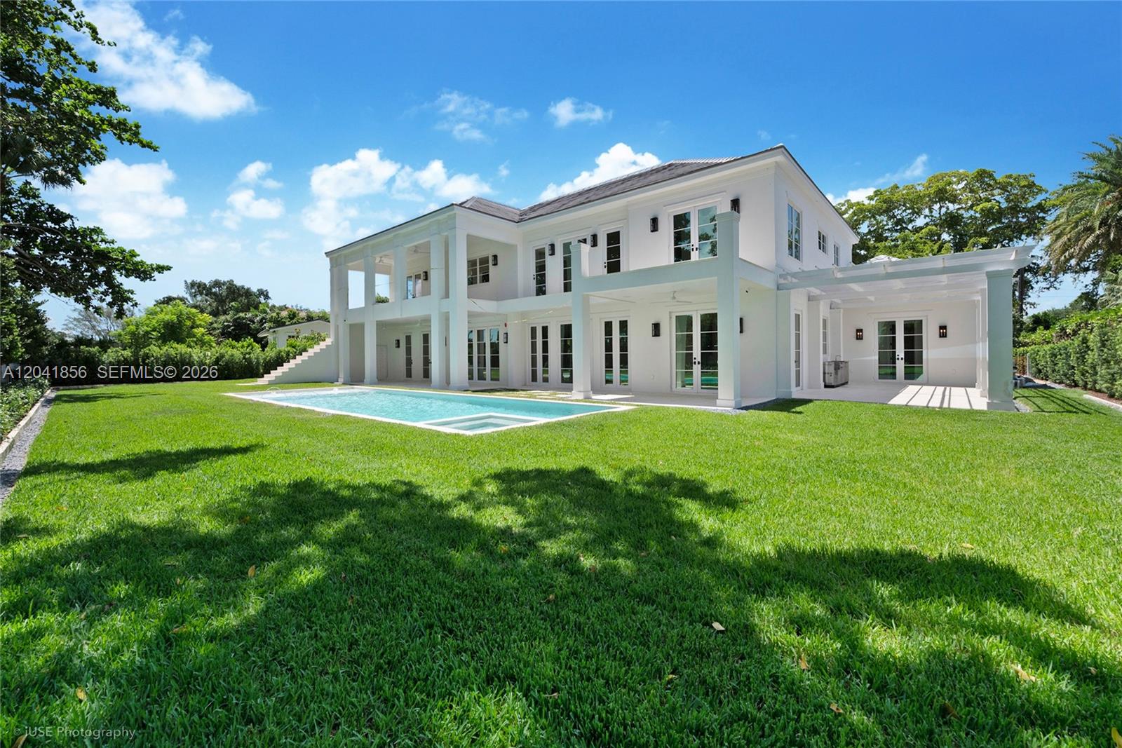 The exterior of a two-story white house features a swimming pool and a grassy lawn — 1241 Mariola Ct, Coral Gables FL 33134, CORAL GABLES, FL