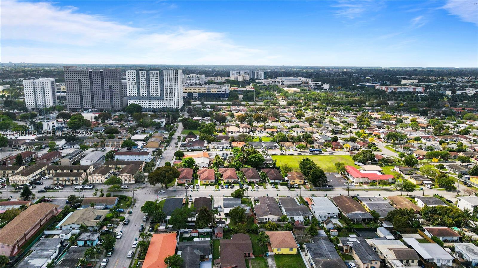 An aerial view shows a suburban neighborhood with houses, apartment complexes, and distant city buildings — 11034 SW 3rd St, Sweetwater FL 33174, SWEETWATER, FL