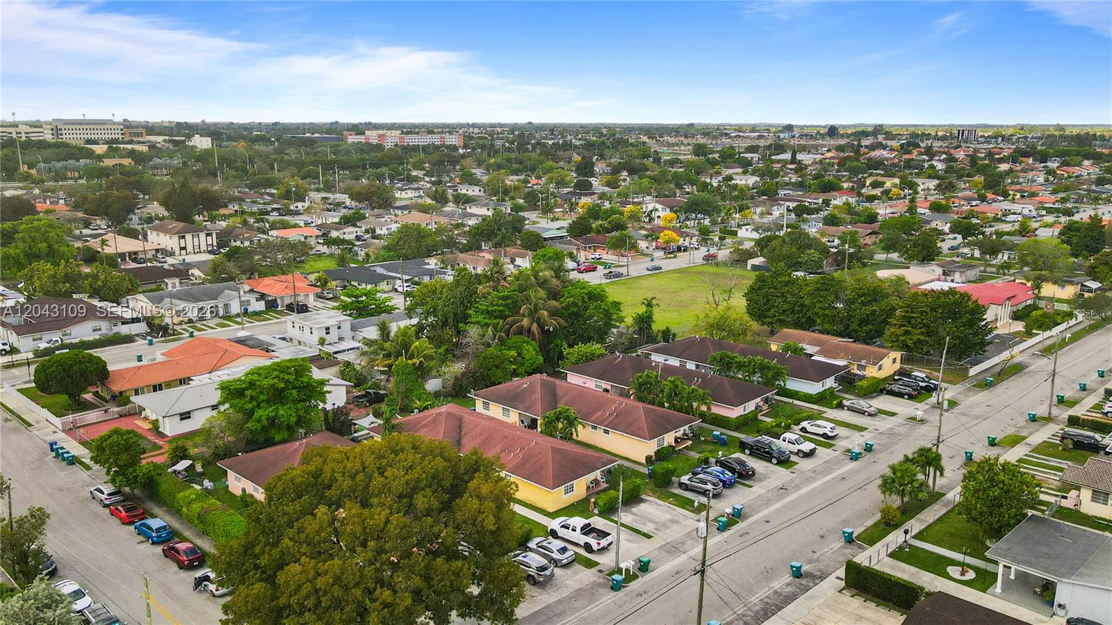 An aerial view shows a suburban neighborhood with single-family homes, streets, and parked cars — 11034 SW 3rd St, Sweetwater FL 33174, SWEETWATER, FL
