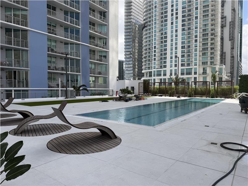 A rectangular swimming pool sits on a paved deck surrounded by modern high-rise apartment buildings — 335 S Biscayne Boulevard # 4004, Miami FL 33131, MIAMI, FL