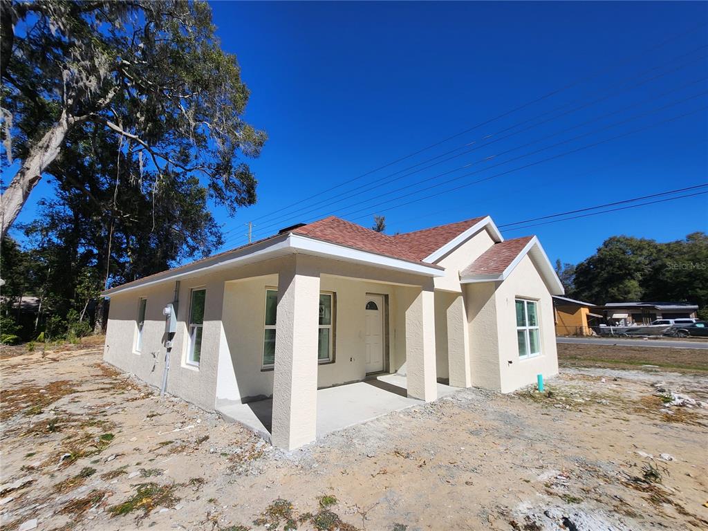 A newly constructed, light-colored stucco house with a brown shingled roof and a front porch — 3591 SE 139TH STREET, SUMMERFIELD, FL