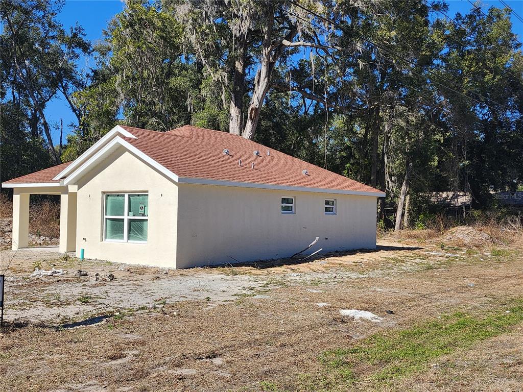 A single-story house with light-colored stucco walls and a covered front porch under construction — 3591 SE 139TH STREET, SUMMERFIELD, FL