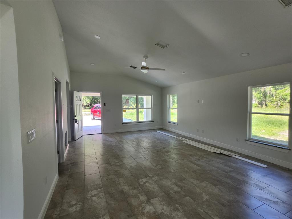 A newly constructed, light-colored house with a brown shingled roof stands on a dirt lot — 3591 SE 139TH STREET, SUMMERFIELD, FL