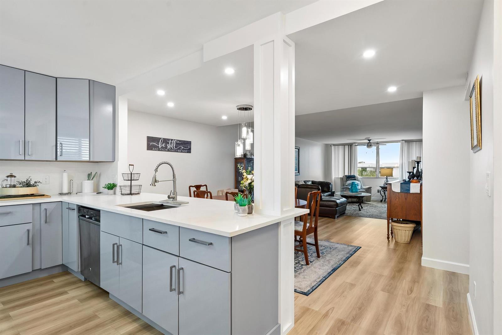 A kitchen with light blue cabinets and white countertops opens into a dining and living area — 6698 10th Avenue N # 408, FL 33467, FL