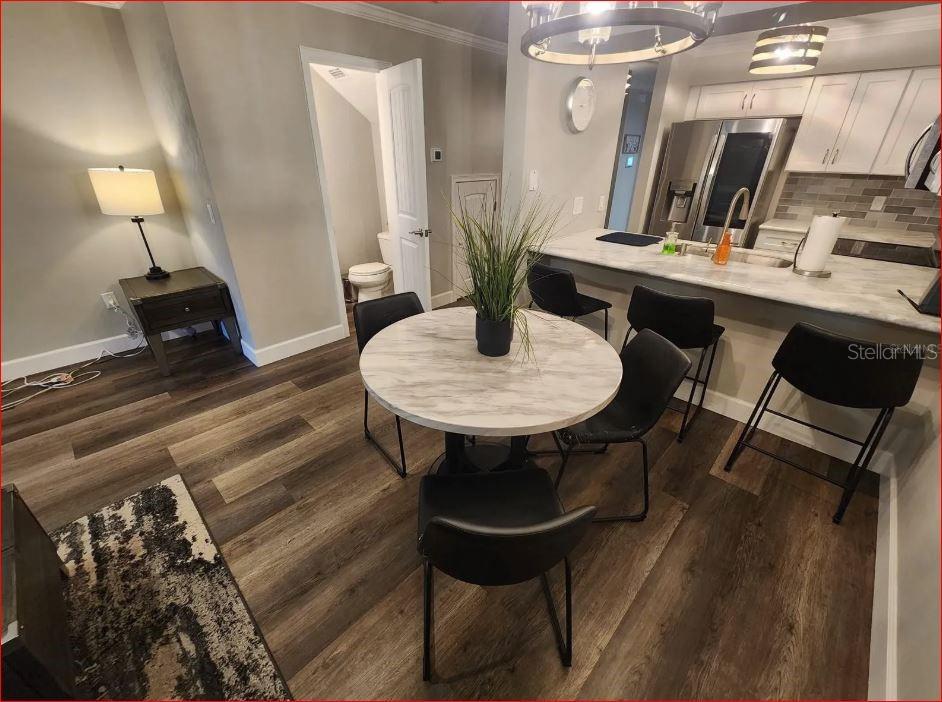 A dining area with a round table and chairs sits adjacent to a modern kitchen — 2735 SW 35TH PLACE UNIT 804, GAINESVILLE, FL