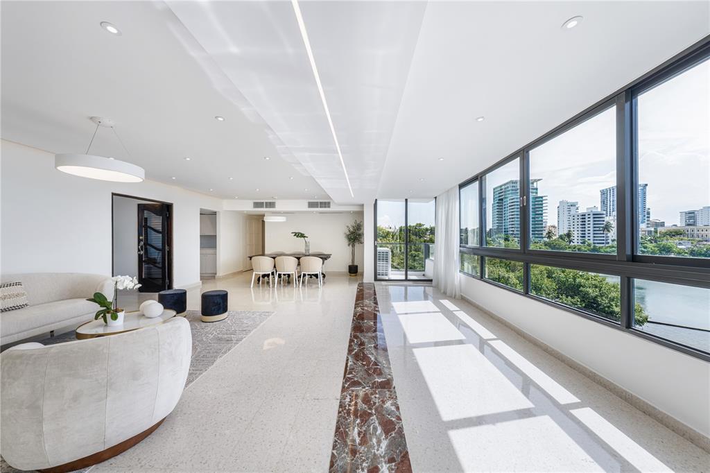 A modern living and dining area with marble floors, large windows, and city skyline views — 20 DELCASSE STREET UNIT 401, SAN JUAN, PR