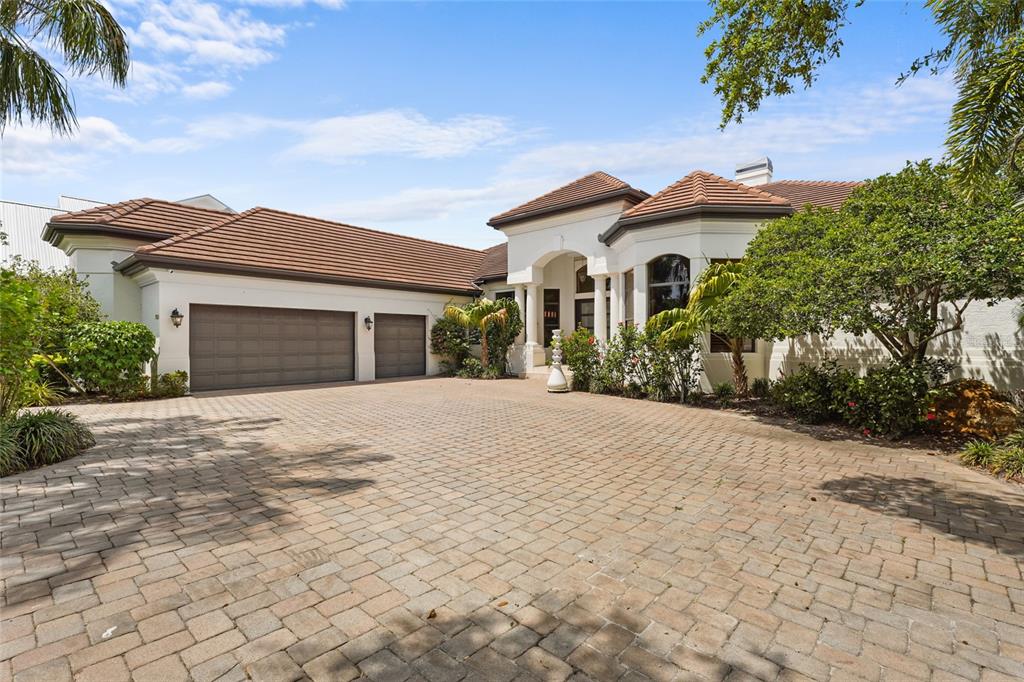 A single-story house with a tile roof, three-car garage, and a large paved driveway — 7610 DESOTO MEMORIAL HIGHWAY, BRADENTON, FL