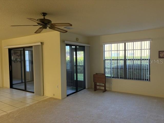A living room features beige carpet, a ceiling fan, sliding glass doors, and vertical blinds — 4809 WAKEFIELD COURT, NEW PORT RICHEY, FL