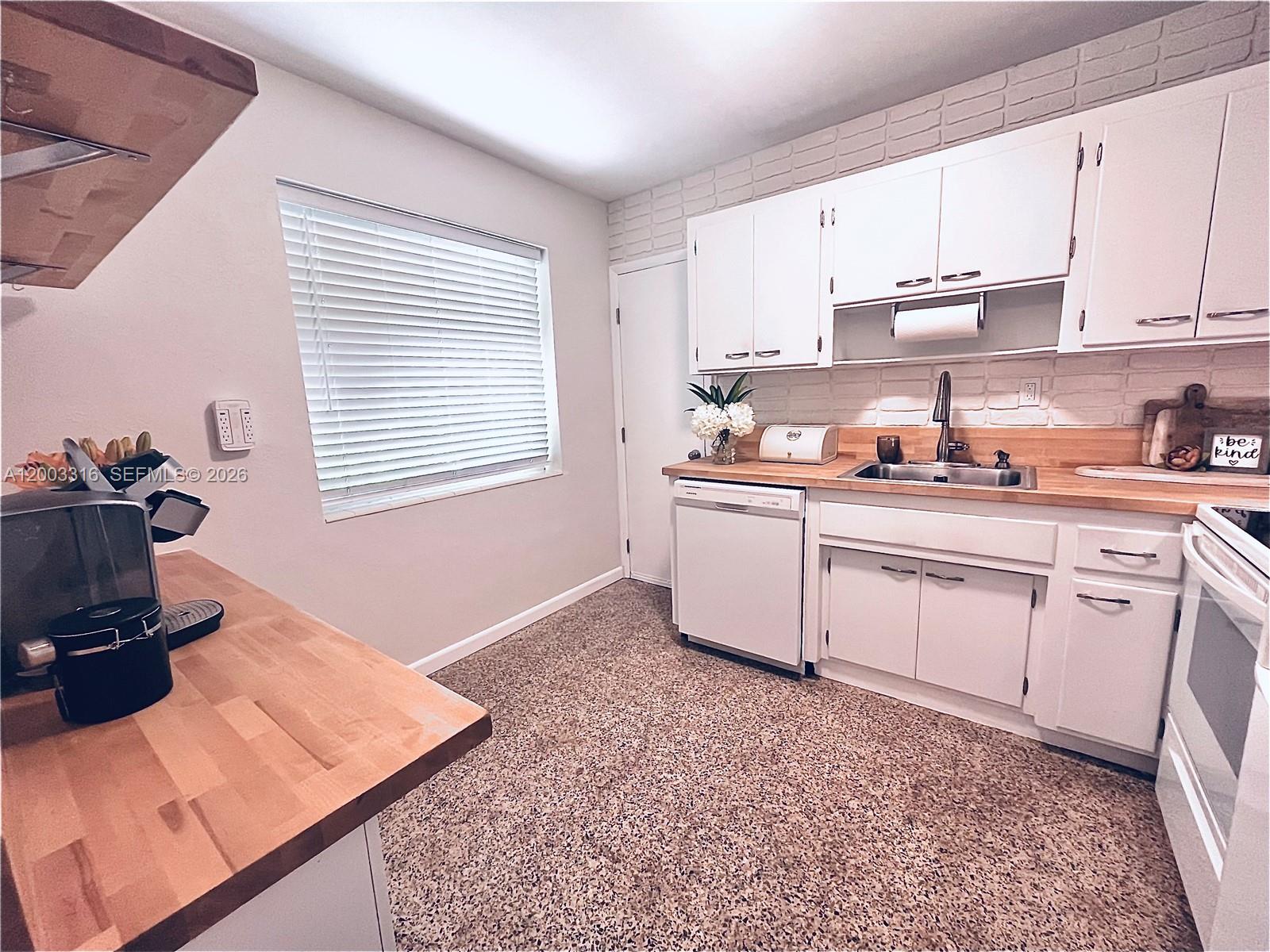 A kitchen features white cabinets, butcher block countertops, a brick backsplash, and speckled flooring — 9840 SW 165th Ter, Miami FL 33157, MIAMI, FL