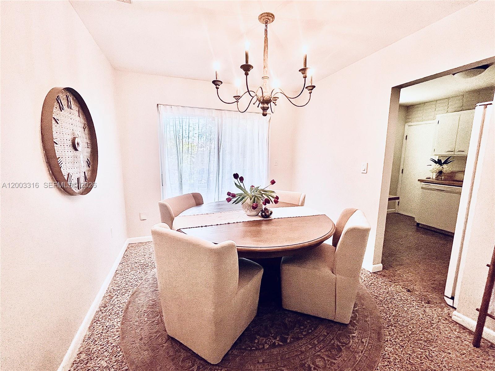 A dining room features a round wooden table, four upholstered chairs, and a chandelier — 9840 SW 165th Ter, Miami FL 33157, MIAMI, FL