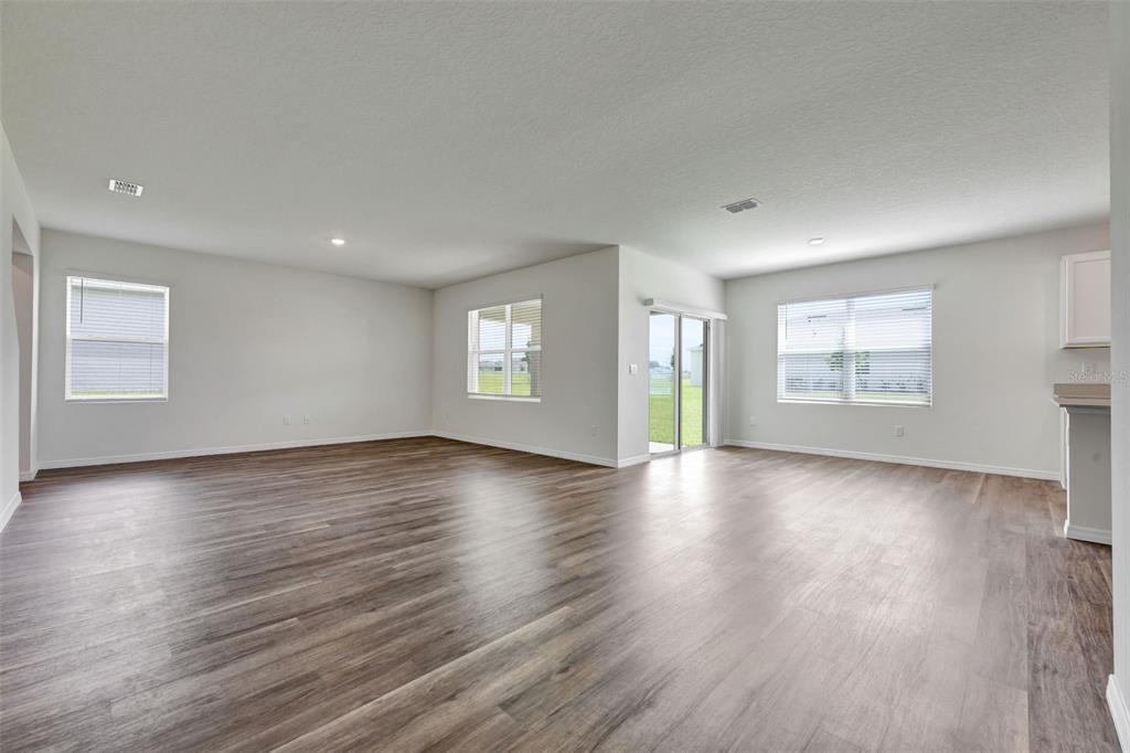 An open-concept living area features light gray walls, wood-look flooring, and several windows — 3521 RODEN ROAD, HAINES CITY, FL