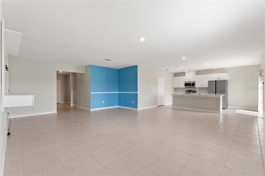 An open-concept living area features light-colored tile flooring, a blue accent wall, and a kitchen — 4201 CALLIANDRA DRIVE, INDIAN LAKE ESTATES, FL