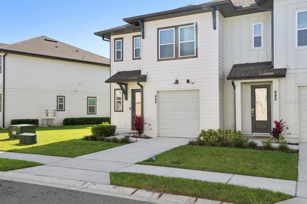 The exterior of a two-story townhouse with white siding, a garage, and a front walkway — 646 LONGBOAT DRIVE, DAVENPORT, FL