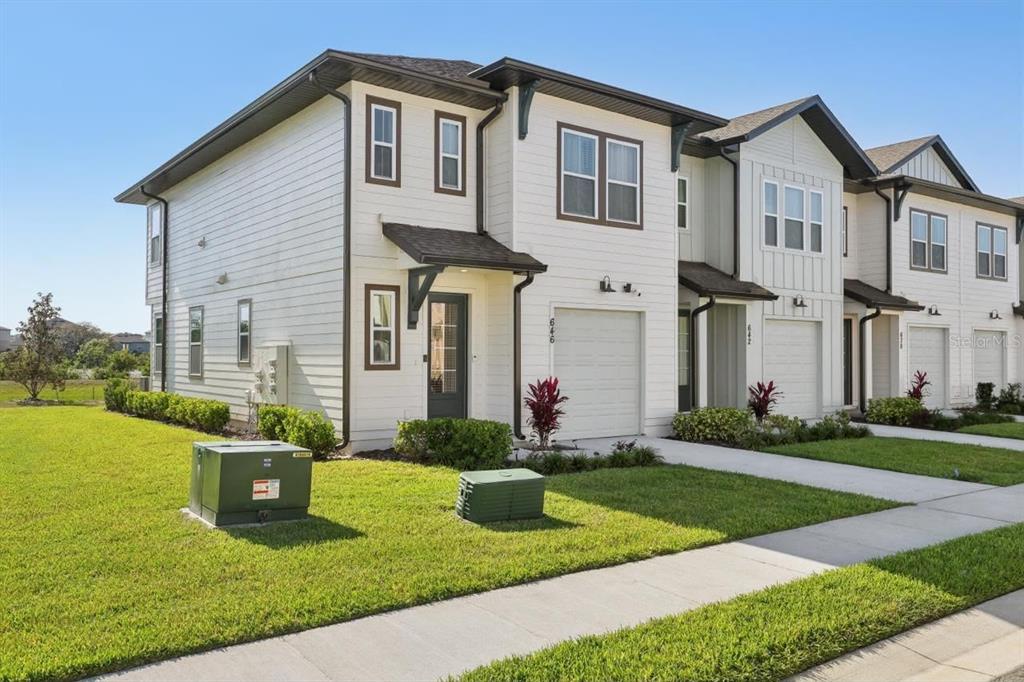 A two-story townhouse with white horizontal siding, a single-car garage, and a green lawn — 646 LONGBOAT DRIVE, DAVENPORT, FL