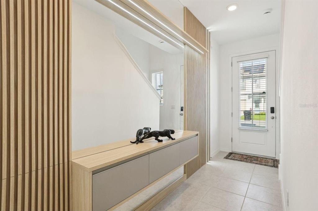 An entryway features a floating console table, vertical wood slat wall panels, and a large mirror — 646 LONGBOAT DRIVE, DAVENPORT, FL