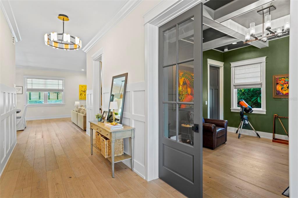 A hallway with light wood floors leads to a living area and a green office — 2403 CAMBRIDGE AVENUE, LAKELAND, FL