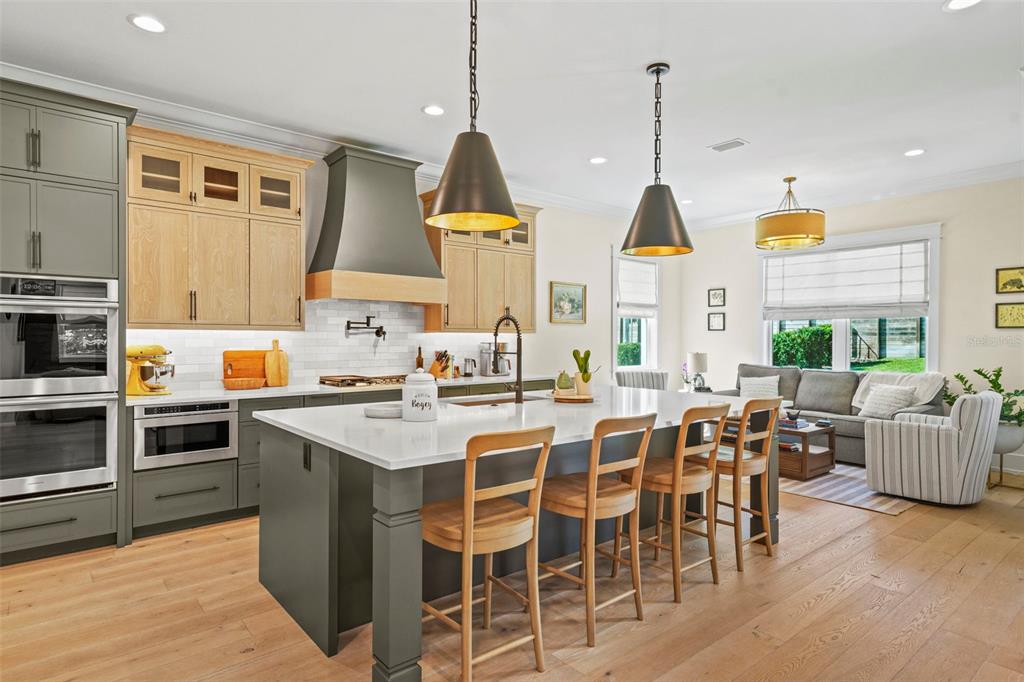 A kitchen features a large island, two-tone cabinetry, stainless steel appliances, and wood flooring — 2403 CAMBRIDGE AVENUE, LAKELAND, FL