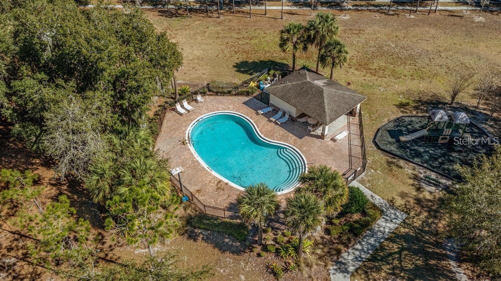 An aerial view shows a kidney-shaped swimming pool, a covered pavilion, and a playground area — 2896 TANZANITE TERRACE, KISSIMMEE, FL