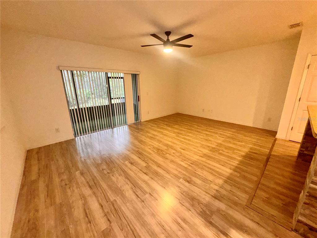An empty room with wood-look flooring, a ceiling fan, and sliding glass doors — 2896 TANZANITE TERRACE, KISSIMMEE, FL