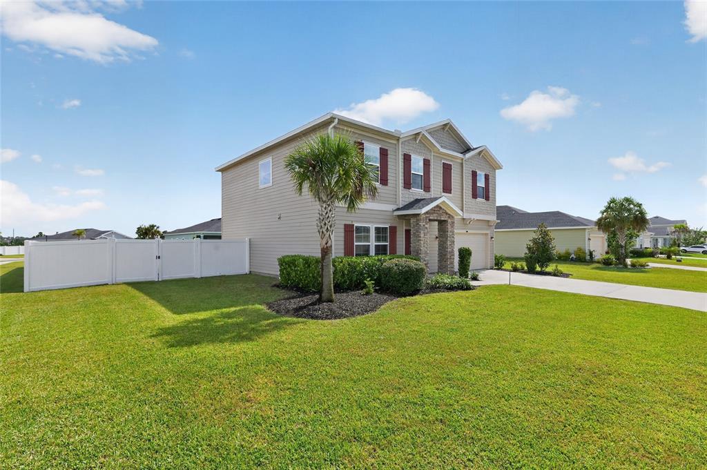 A two-story suburban house with tan siding, a stone entryway, and a white vinyl fence — 5624 SW 93RD STREET, OCALA, FL
