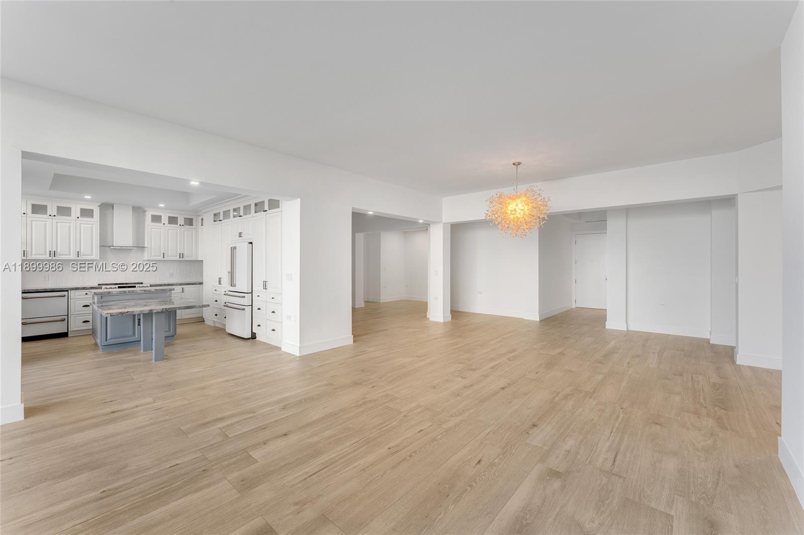 An open-concept living area features light wood flooring, white walls, and a modern kitchen — 848 Brickell Key Dr # 204, Miami FL 33131, MIAMI, FL