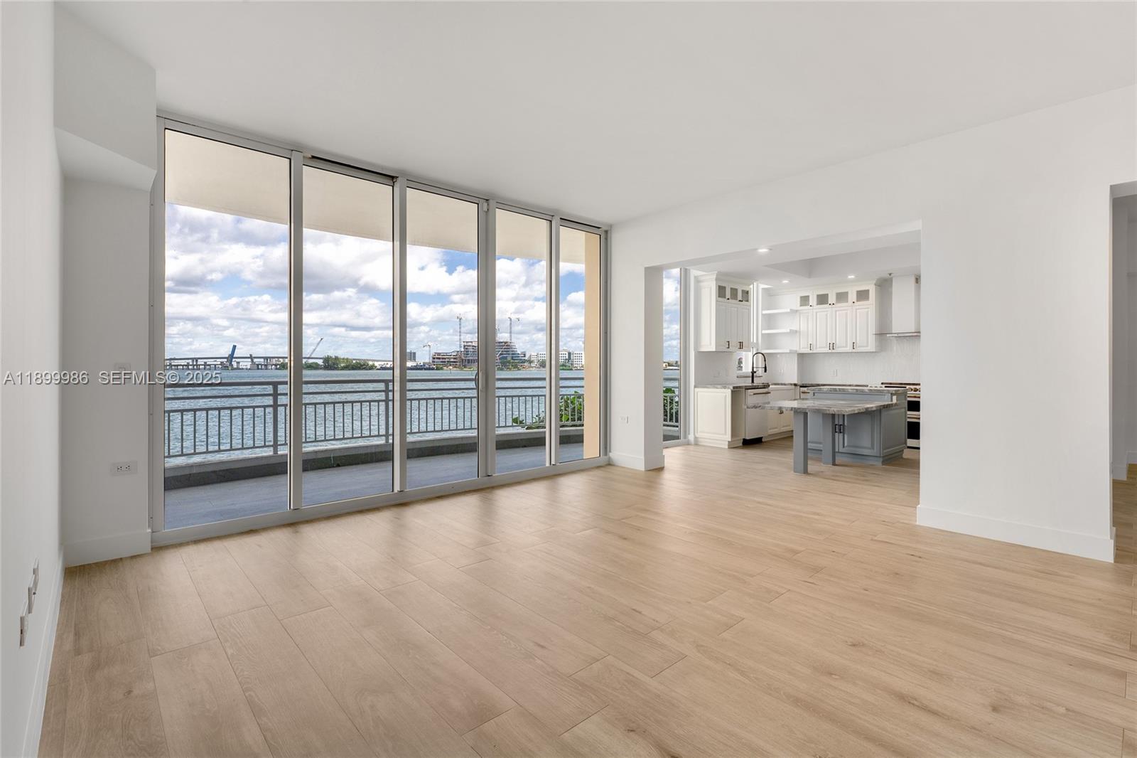 An open-concept living area features light wood flooring, floor-to-ceiling windows, and a modern kitchen — 848 Brickell Key Dr # 204, Miami FL 33131, MIAMI, FL