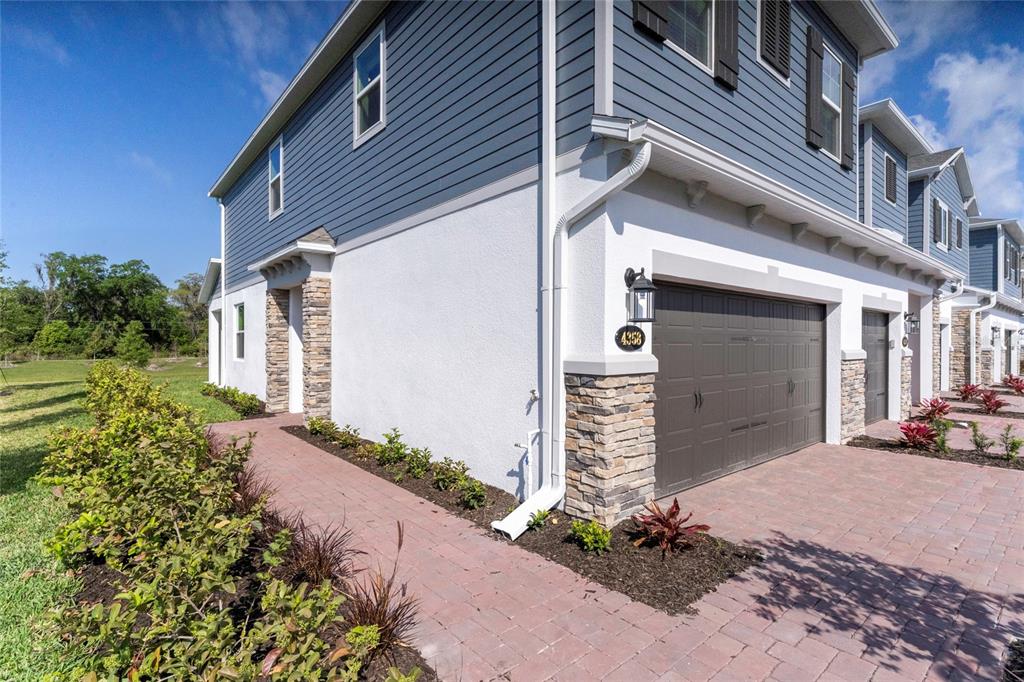 The exterior of a two-story townhouse features blue siding, white stucco, and a stone facade — 4358 CAMPSITE LOOP, ORLANDO, FL