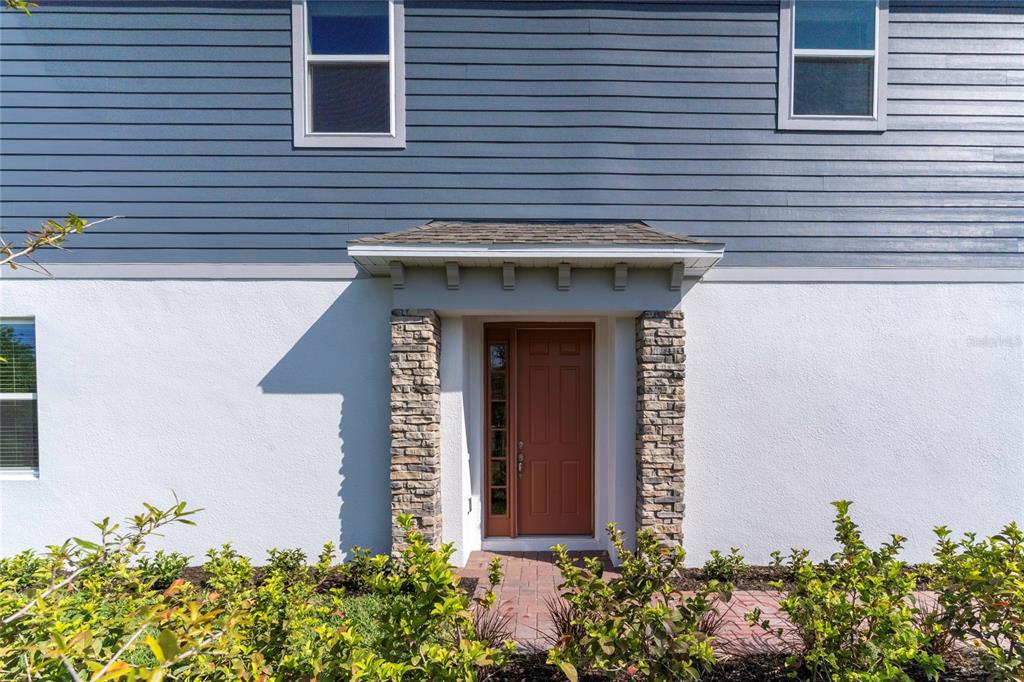 The exterior of a house features blue horizontal siding, white stucco, and a stone-accented entryway — 4358 CAMPSITE LOOP, ORLANDO, FL