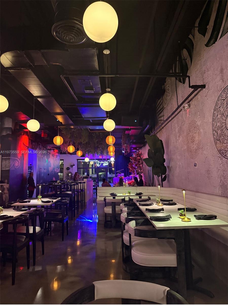 A restaurant interior features white tables, modern globe pendant lighting, and a textured accent wall — 12850 sw 128th st, Miami FL 33186, MIAMI, FL