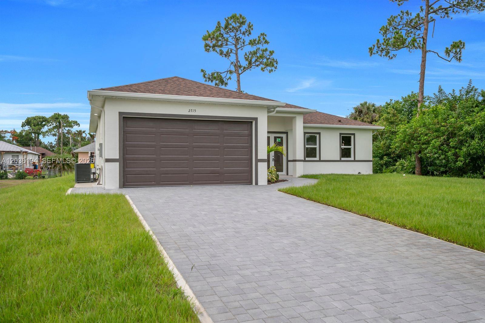 A single-story house with a paved driveway, brown garage door, and light-colored exterior walls — 2715 10th ST W, Lehigh Acres FL 33971, LEHIGH ACRES, FL