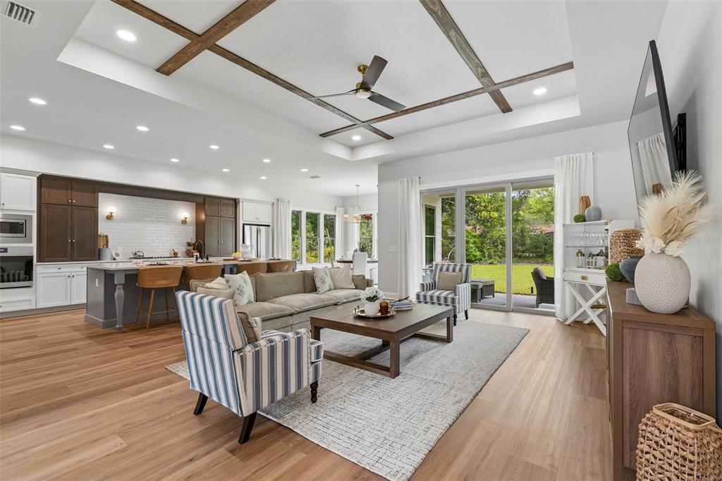 A spacious open-concept living room and kitchen featuring wood-beamed ceilings and hardwood flooring — 14098 SW 7TH PLACE, NEWBERRY, FL