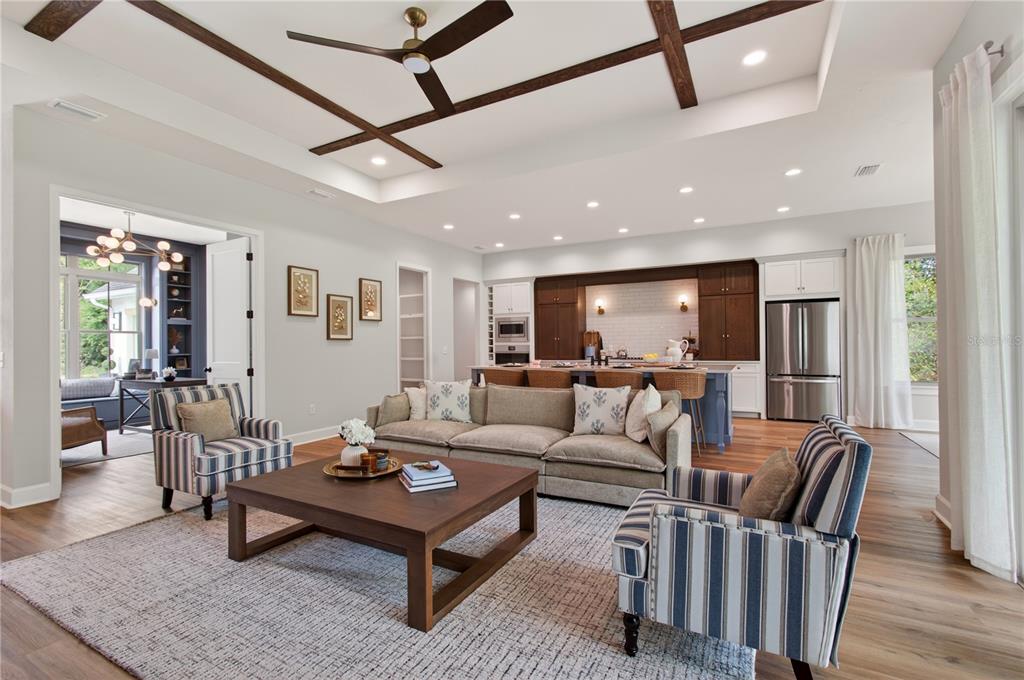 A living room with a coffered ceiling, striped armchairs, and an open kitchen beyond — 14098 SW 7TH PLACE, NEWBERRY, FL