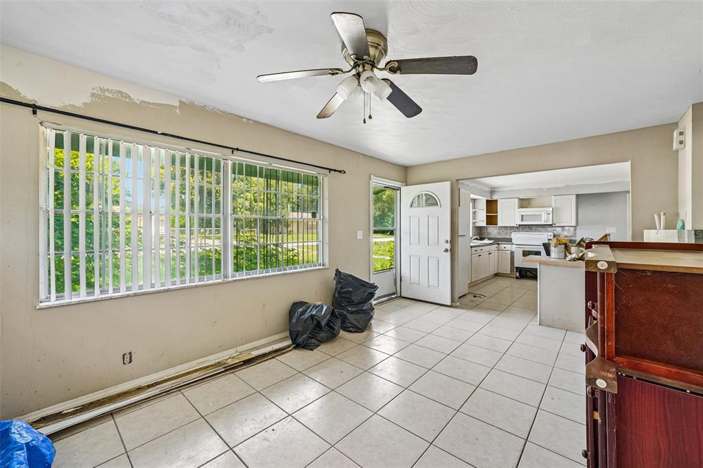 A tiled dining area with a ceiling fan, large windows, and an adjacent kitchen — 18748 ROSEPHIL ST, SPRING HILL, FL