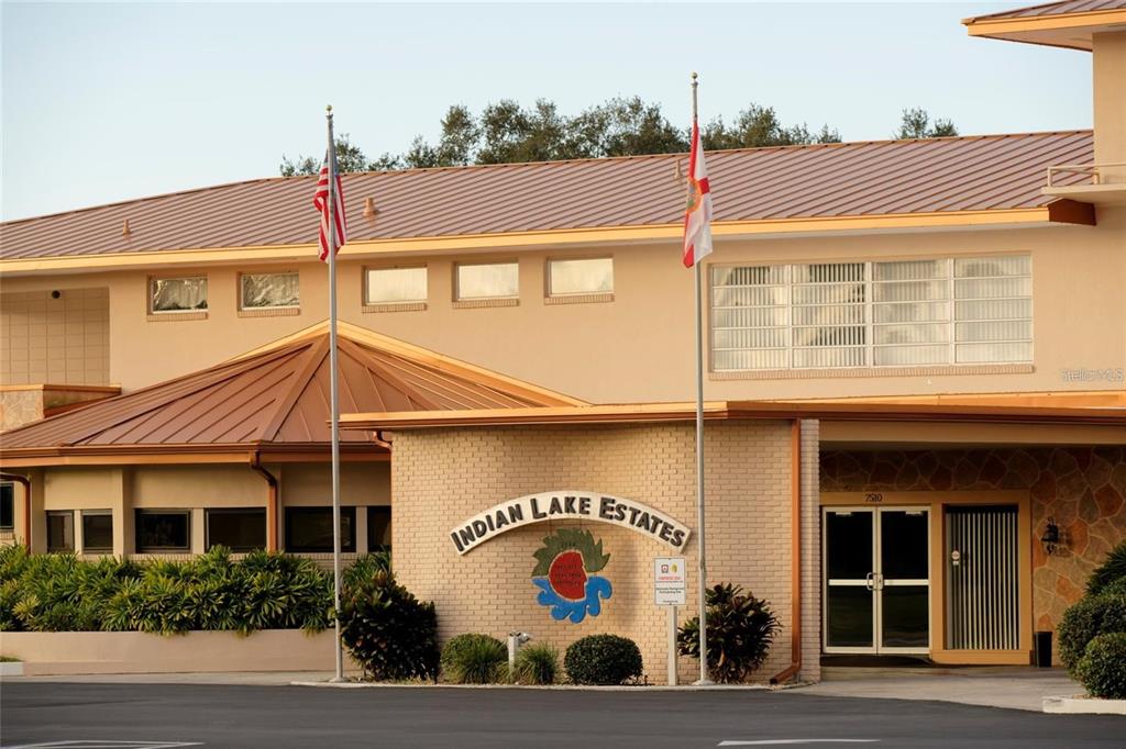 The exterior of a tan building features a brick facade with a logo and two flagpoles — 2 LAGUNA DRIVE, INDIAN LAKE ESTATES, FL