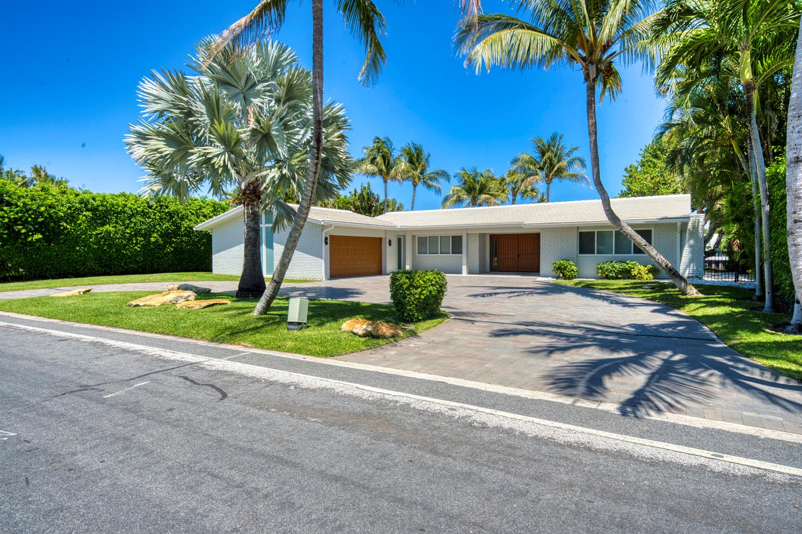 A single-story white brick house with a paved driveway and palm trees under a blue sky — 2259 Ibis Isle Road E, Palm Beach FL 33480, PALM BEACH, FL