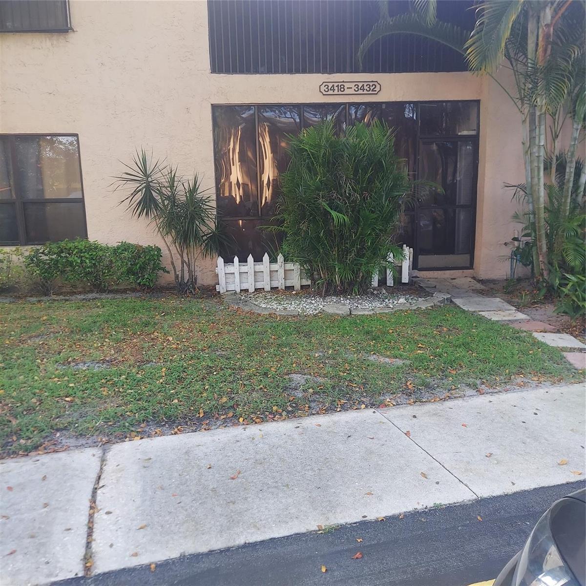 The exterior of a multi-unit residential building features a small garden bed with a white fence — 3420 NW 47th Avenue # 3143, Pompano Beach FL 33063, POMPANO BEACH, FL