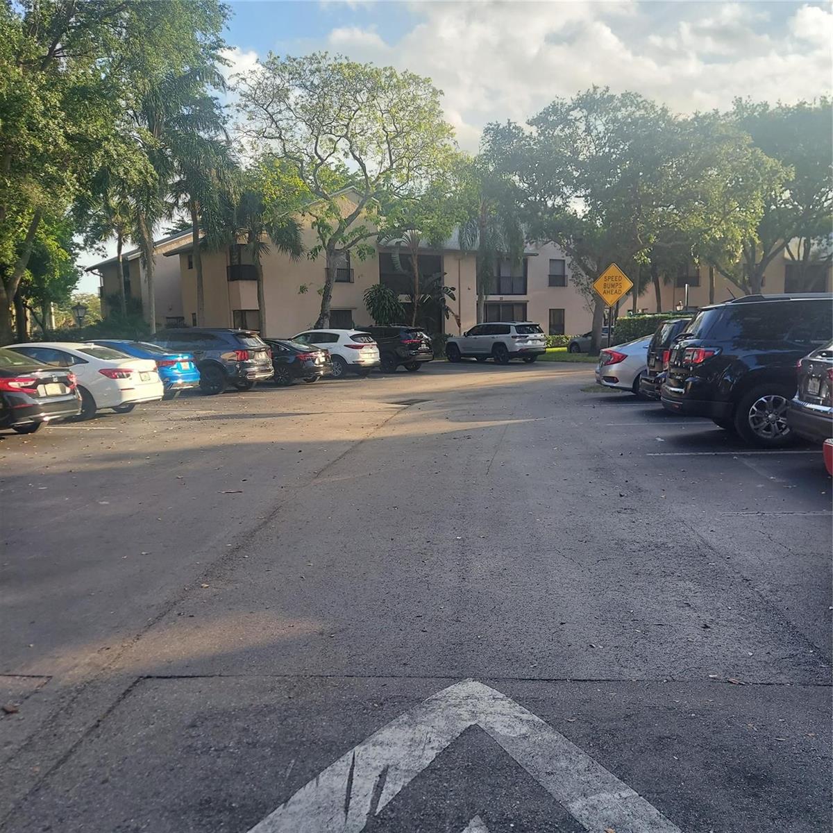 A parking lot with several parked cars in front of a multi-story apartment building — 3420 NW 47th Avenue # 3143, Pompano Beach FL 33063, POMPANO BEACH, FL
