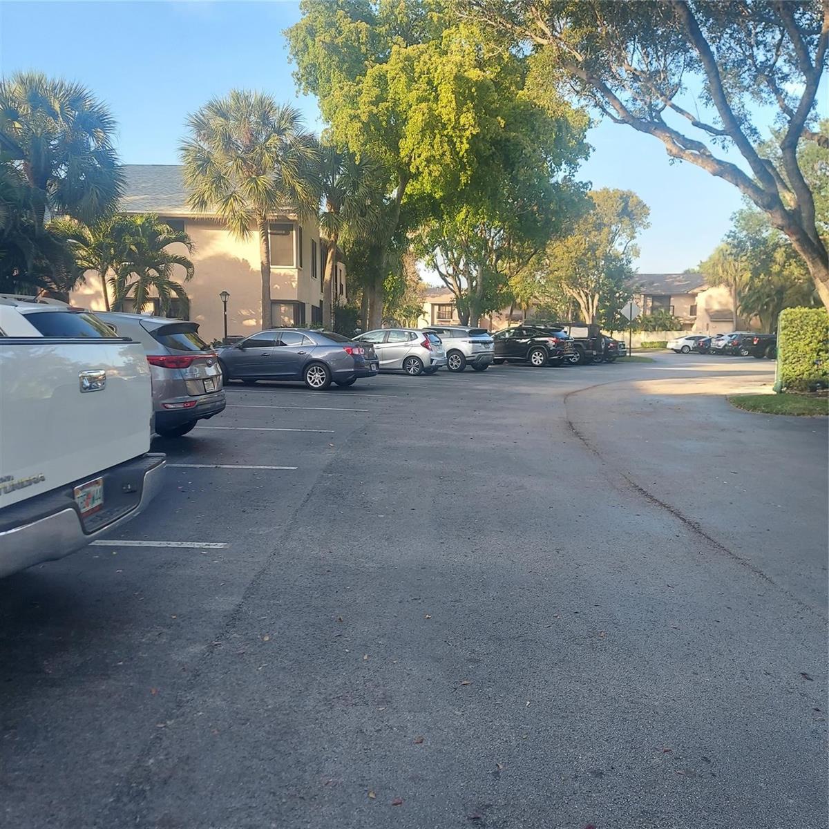 A paved parking lot with several parked cars sits in front of multi-story apartment buildings — 3420 NW 47th Avenue # 3143, Pompano Beach FL 33063, POMPANO BEACH, FL