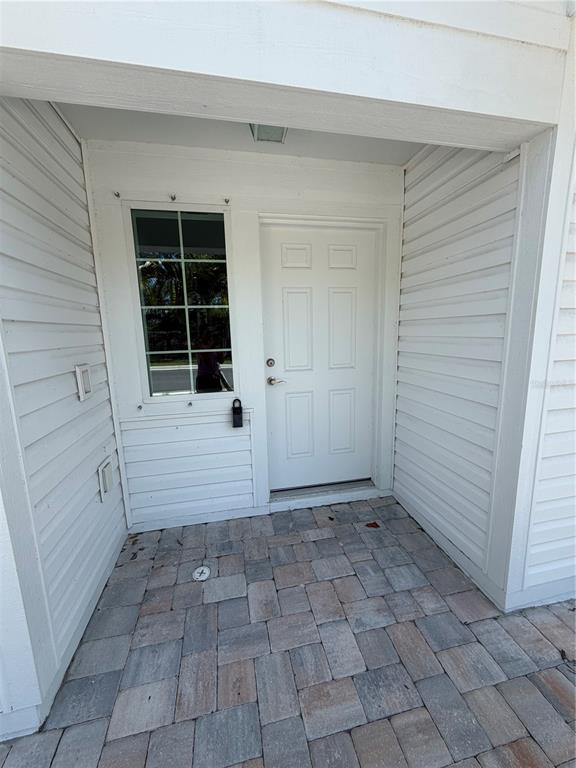 A white front door and a window with a lockbox sit on a paved porch — 2575 6TH AVENUE DRIVE E, BRADENTON, FL