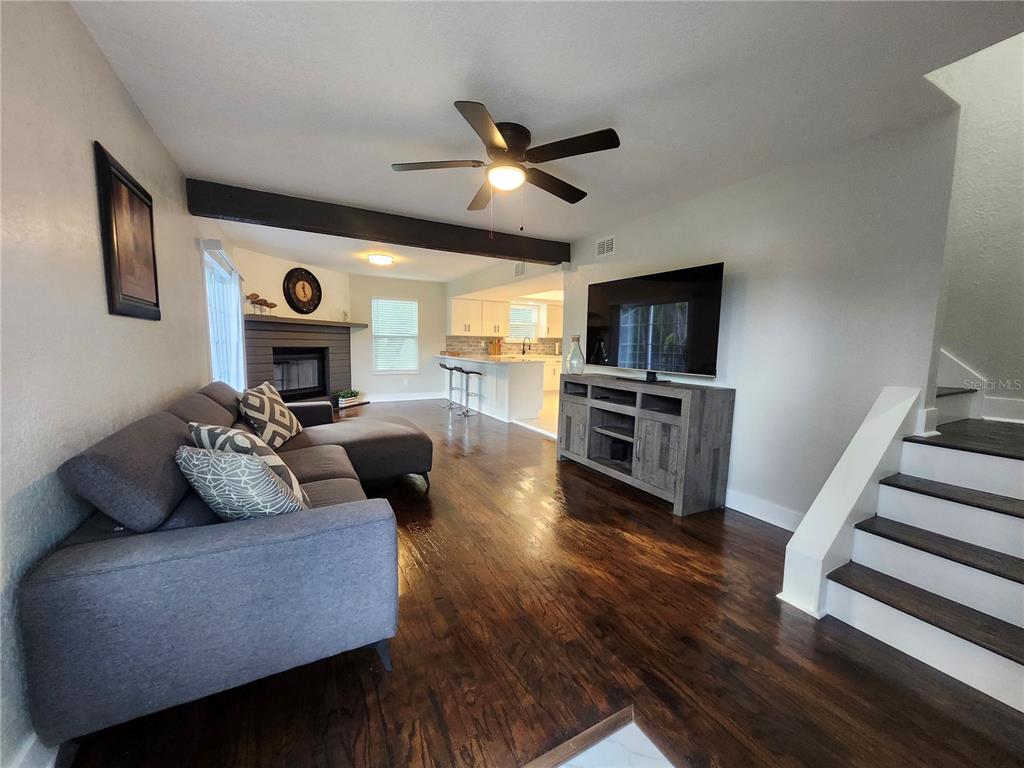 A living room with dark wood floors, a gray sectional sofa, and a fireplace — 3071 HURON AVENUE, OLDSMAR, FL